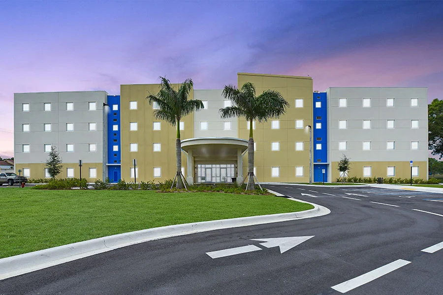 Keiser University student residence with blue facade accents and palm trees at dusk